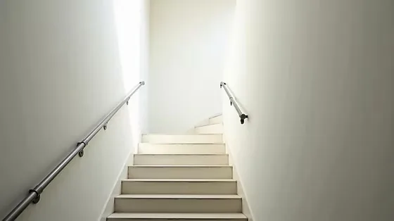 Treppenhausreinigung Berlin, gepflegtes Treppenhaus mit weißen Stufen und Edelstahlgeländer